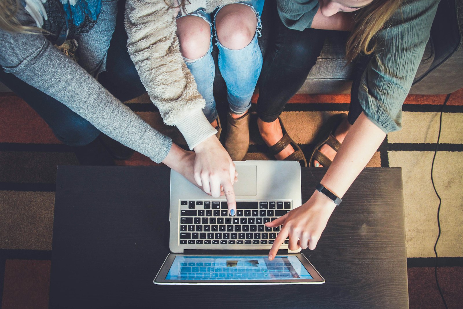 three colleagues gathered around a silver laptop reviewing campaign results together
